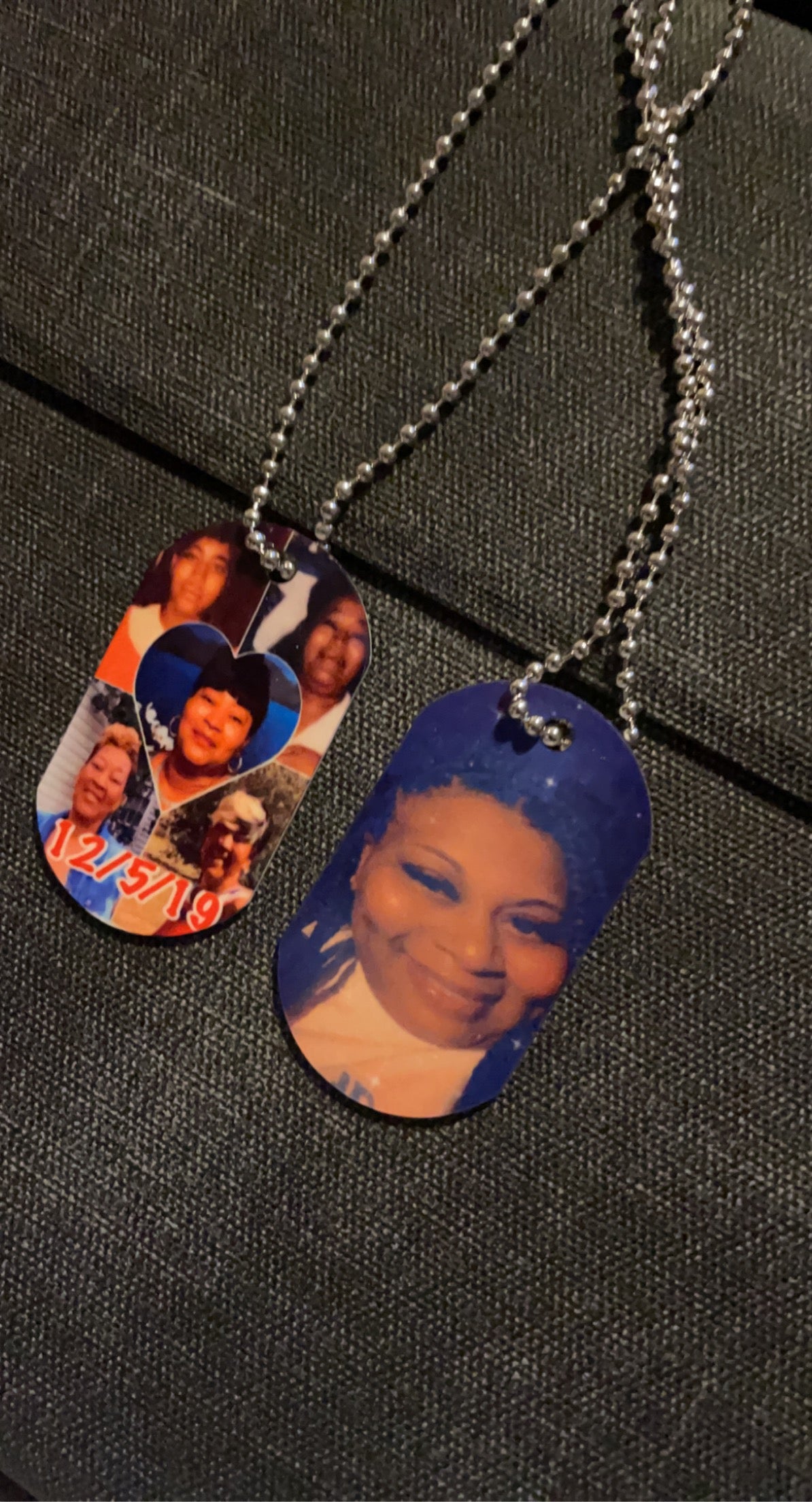 A vertical image showcasing Keep It Sweet & Sassy Designs' Personalized Double-Sided Dog Tags on a dark fabric background. The top personalized accessory features a portrait of a young person with a short haircut, while the bottom tag highlights a group of people in matching white outfits with red lettering, crafted using high-quality sublimation printing.